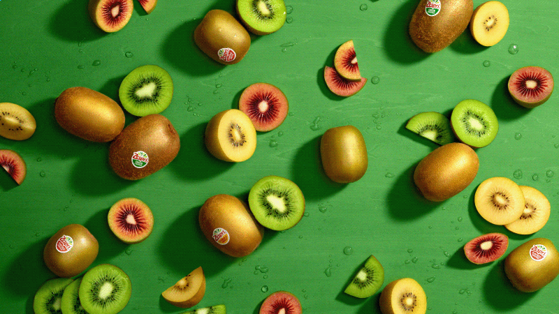 Whole and sliced Green, SunGold and Red kiwifruit on a green background