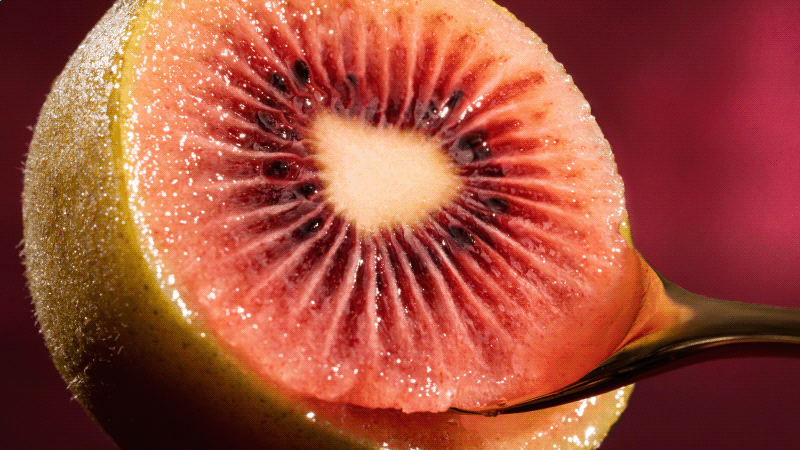Close up of spoon scooping flesh from Red kiwifruit