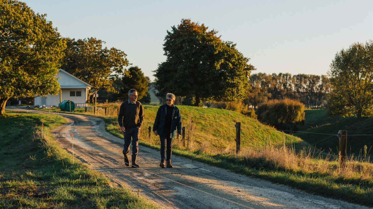 Male and female walking down driveway in front of rural home